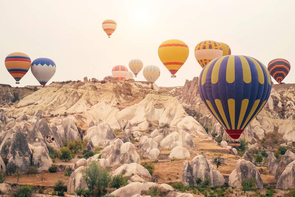 Hot air balloon flying over Cappadocia mountain landscape at gol